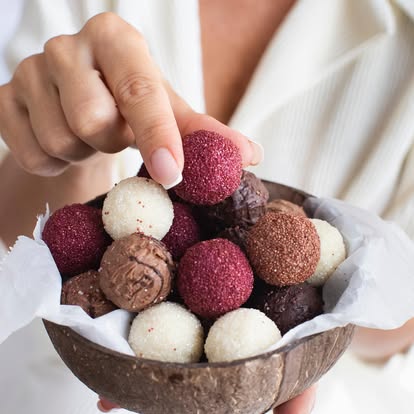Hand holding cocoa-coated chocolate truffles
